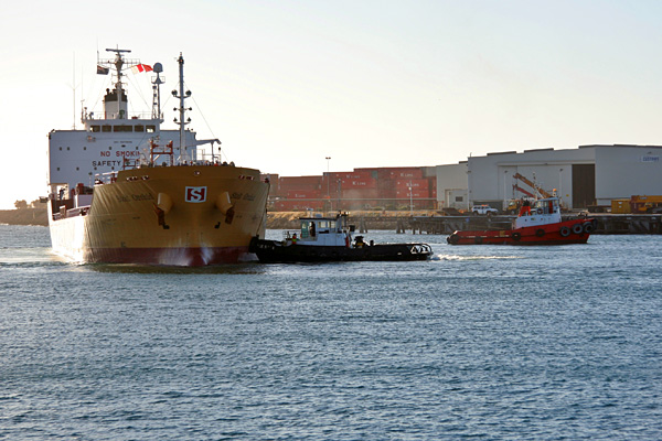 tugboats turning a tanker