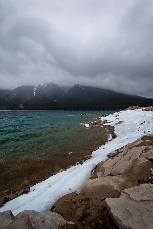 ice lines the banks of Lake Minnewanka