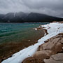 ice lines the banks of Lake Minnewanka